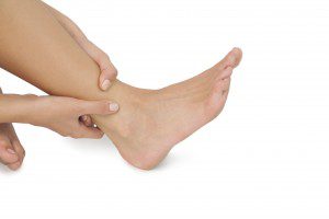 Person holding their lower leg and Achilles tendon area, showing discomfort commonly associated with Achilles tendinitis